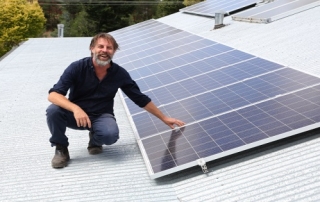 Man on roof next to solar panels